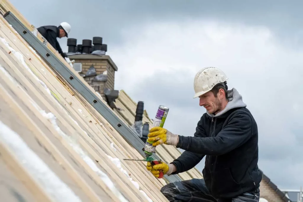 Roofer applying sealant on wood decking during a roof build for roofer marketing calgary